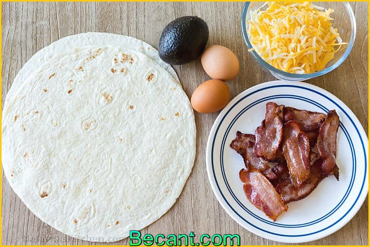 Ingrédients pour préparer des wraps de petit-déjeuner aux tortillas avec des tortillas, du bacon, des œufs, de l'avocat et du fromage