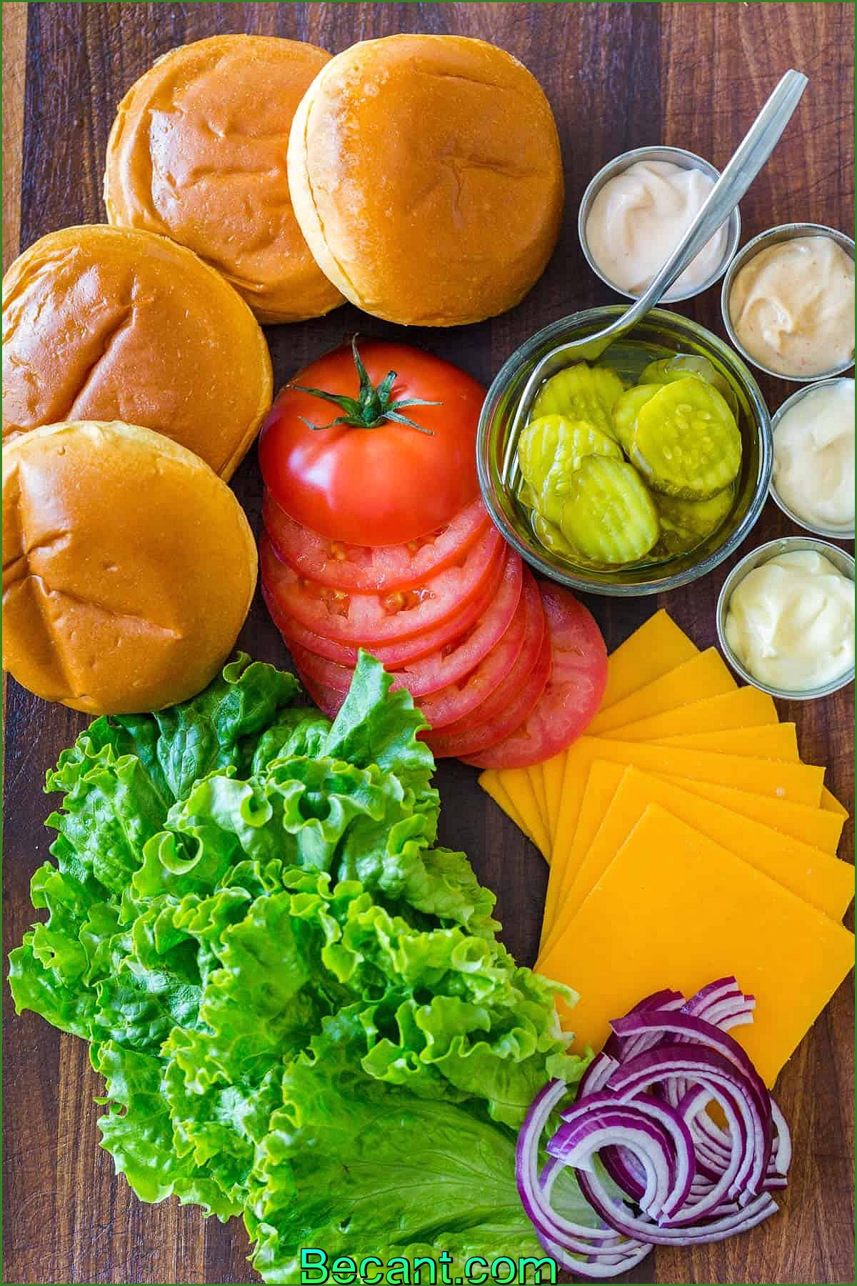 Garnitures de hamburger classiques avec pain, tomates, laitue, fromage, cornichons, oignons rouges et sauces