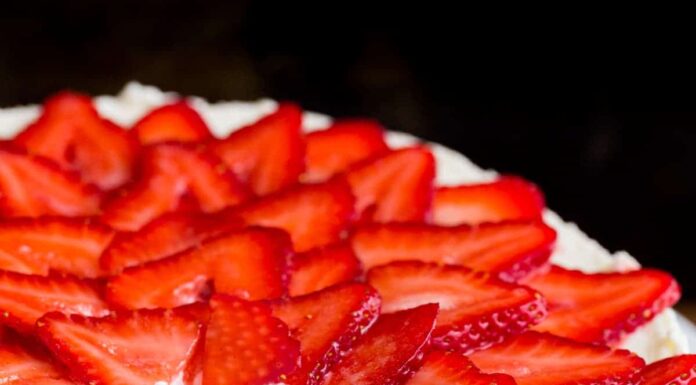 Sliced no bake cheese cake on a serving platter with strawberry topping