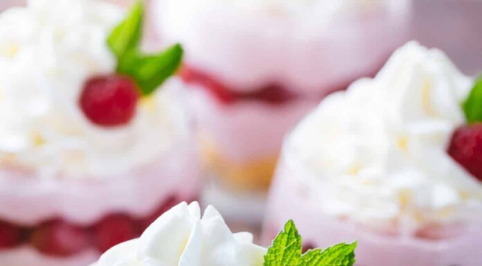 Raspberry mousse served in cups garnished with cream and raspberry